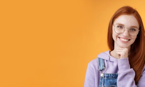 Creative outgoing young charismatic redhead female coworker discuss casual staff smiling laughing happily have pleasant conversation look camera amused tender touch chin, orange background.